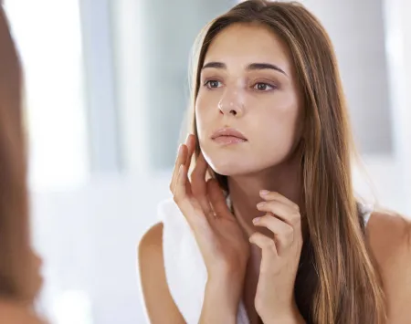 Woman checking her skin in a mirror